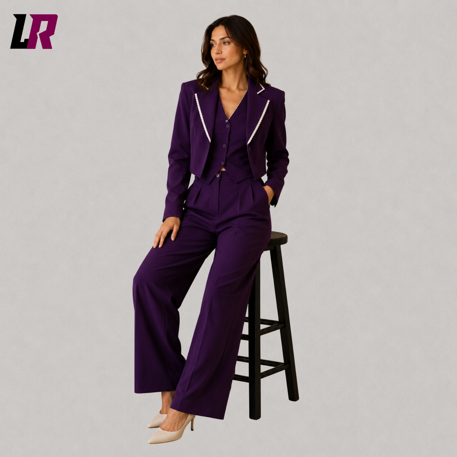 Woman wearing a plum purple three piece suit seated on a stool in a professional portrait