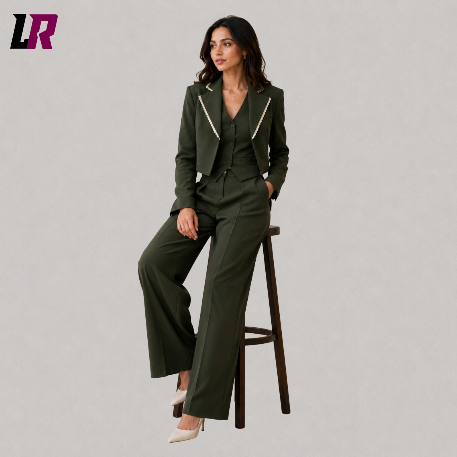 Woman wearing an olive green three piece pantsuit seated on a stool in a professional portrait