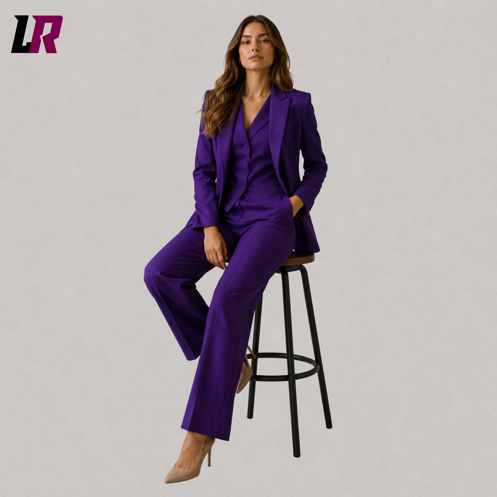 Woman wearing a royal purple formal suit set seated on a stool in a professional portrait