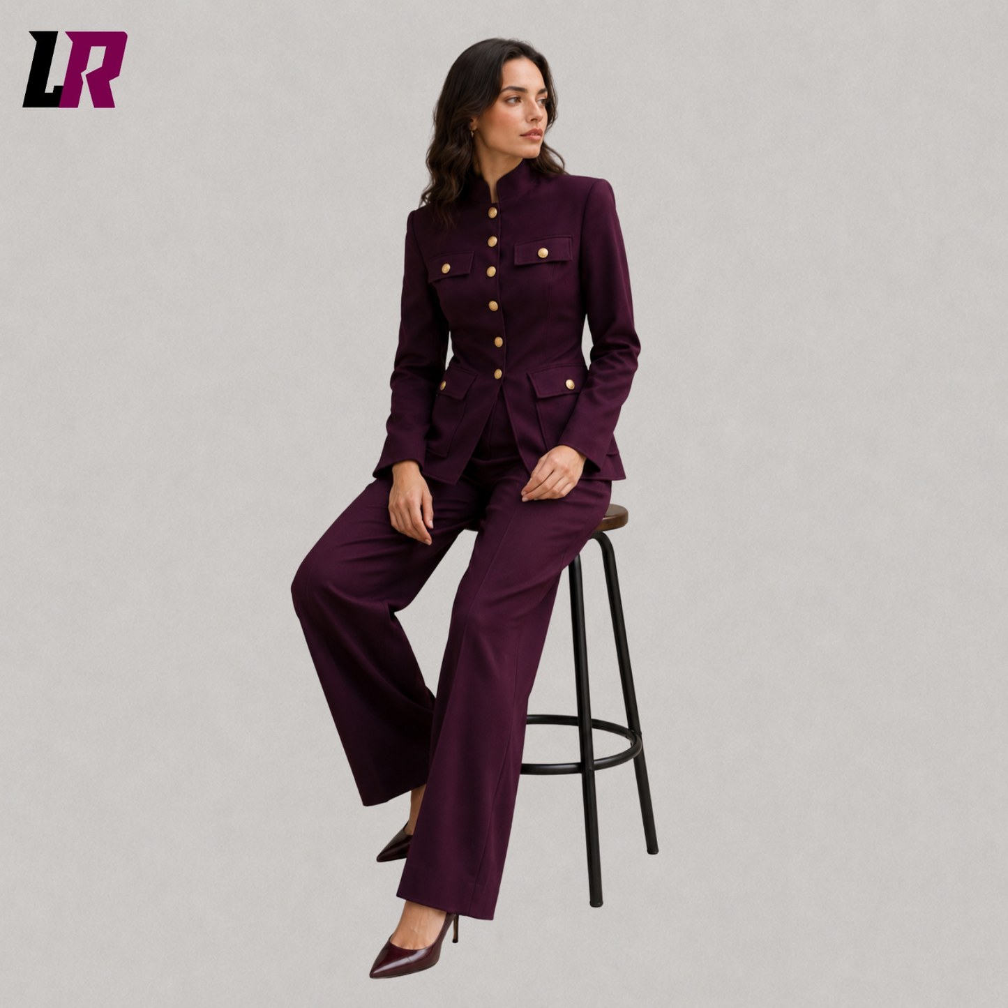 Woman wearing a purple Mandarin collar pantsuit seated on a stool in a formal designer portrait