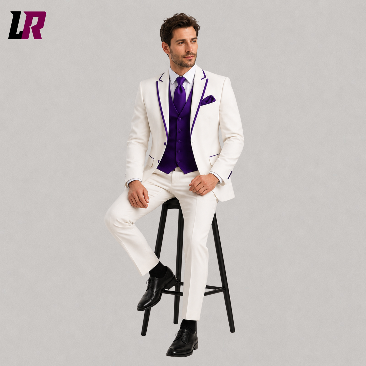 Male model sitting on a wooden stool wearing an ivory wedding tuxedo with a royal purple vest in a luxury studio setting.