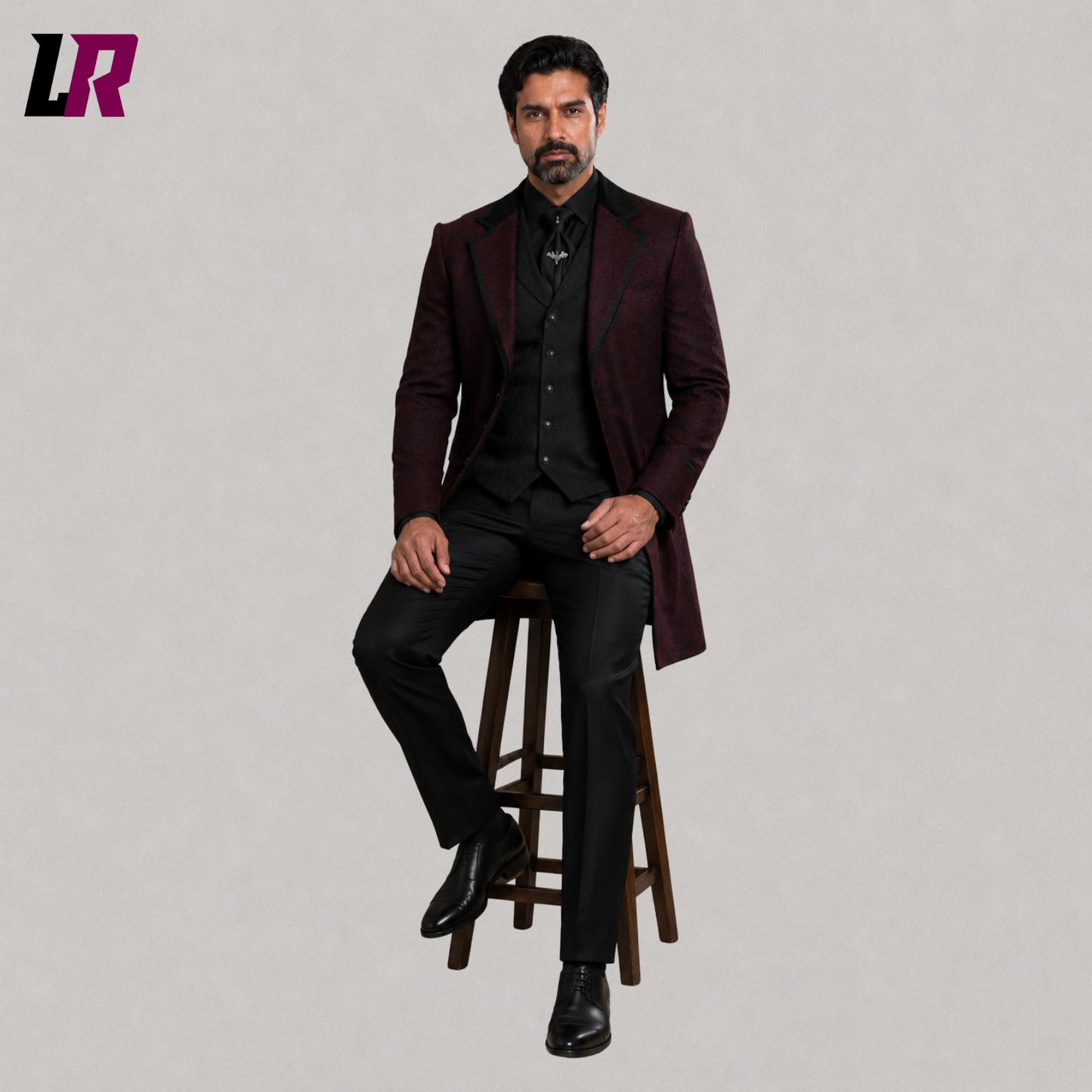 Men's burgundy Gothic brocade blazer with model seated on a stool in a luxury formal fashion pose