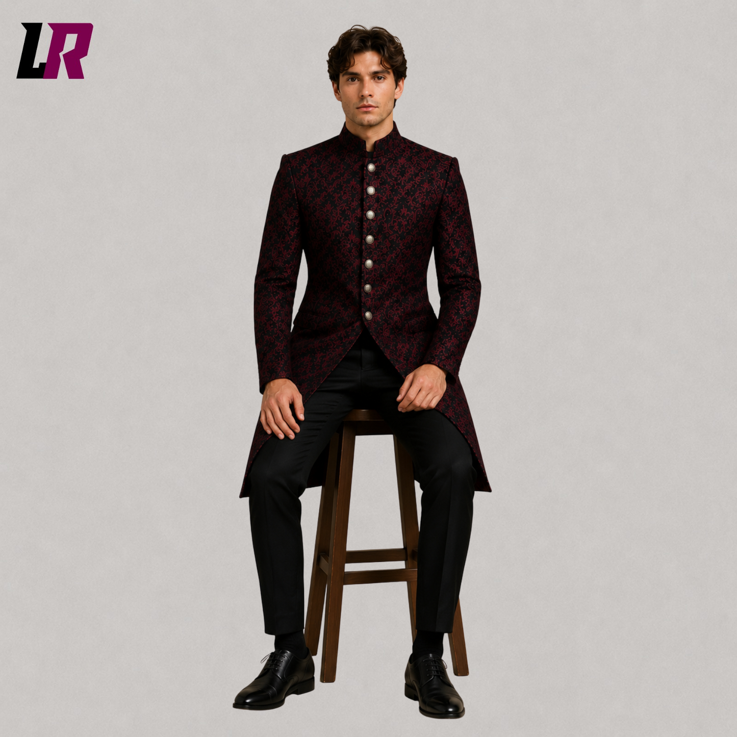 Men's red black brocade long coat with model seated on a stool in a luxury formal fashion pose
