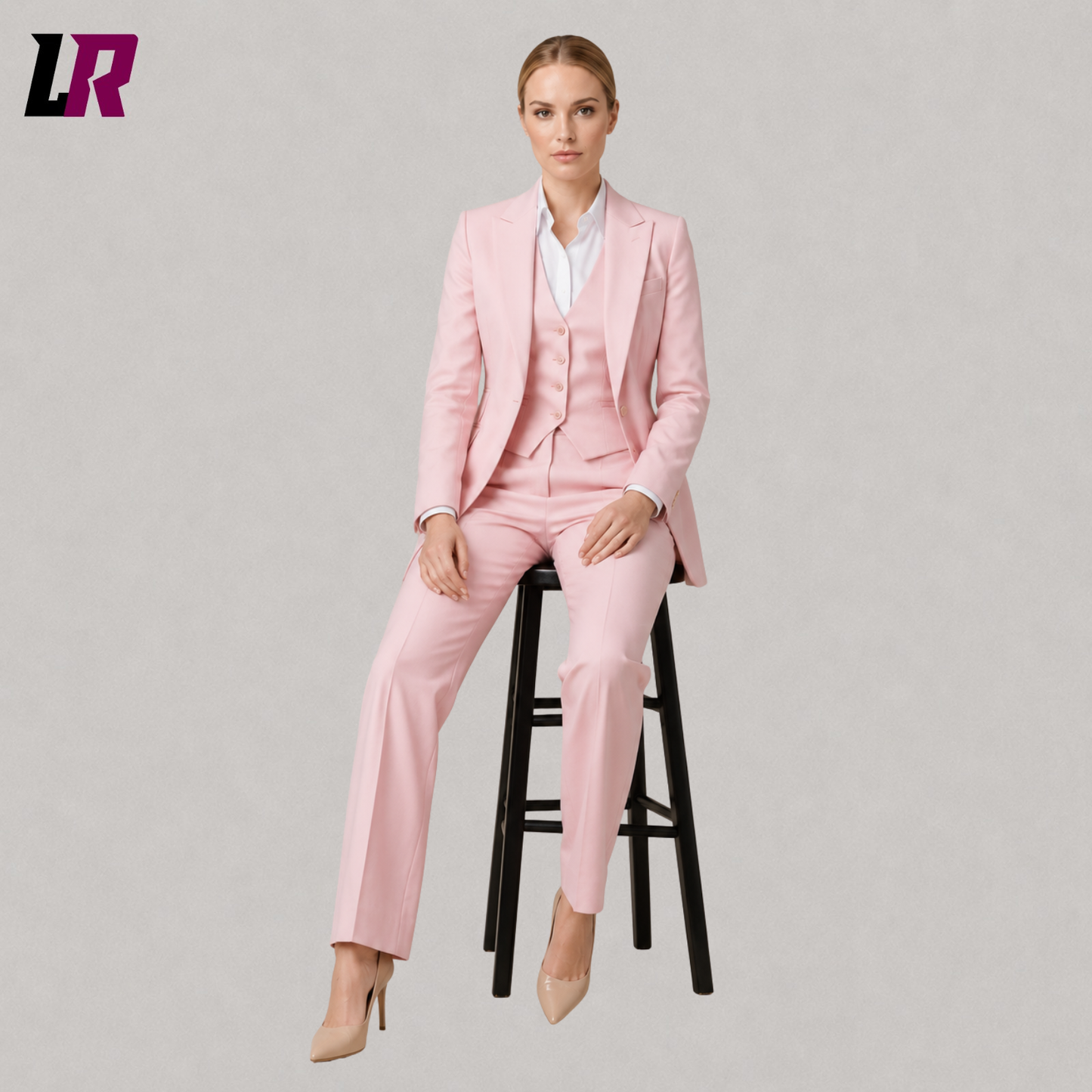 Women's pink tailored 3-piece suit with model seated on a stool in a luxury formal fashion pose