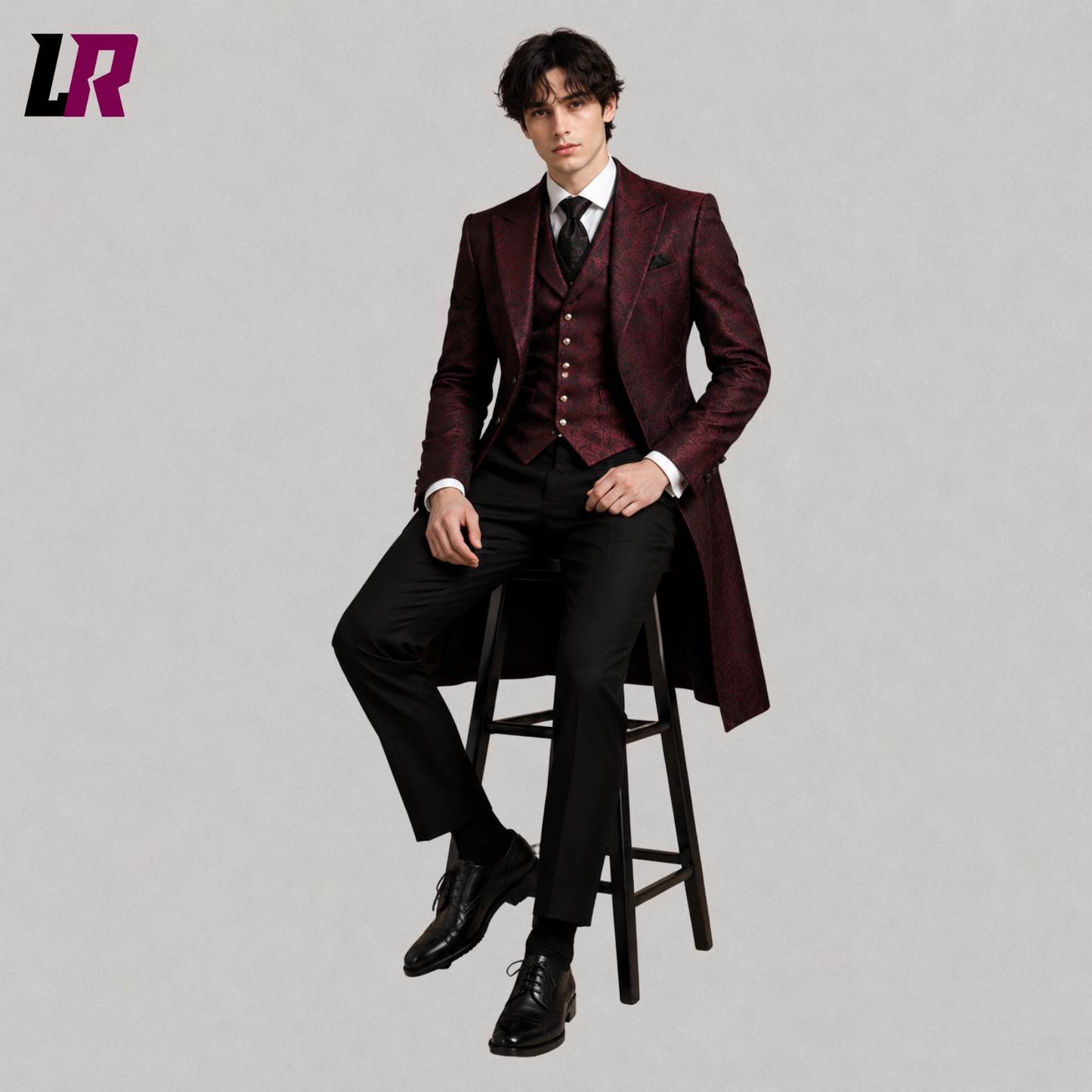 Man sitting on a stool wearing a burgundy Gothic Victorian tailcoat suit for weddings and formal occasions
