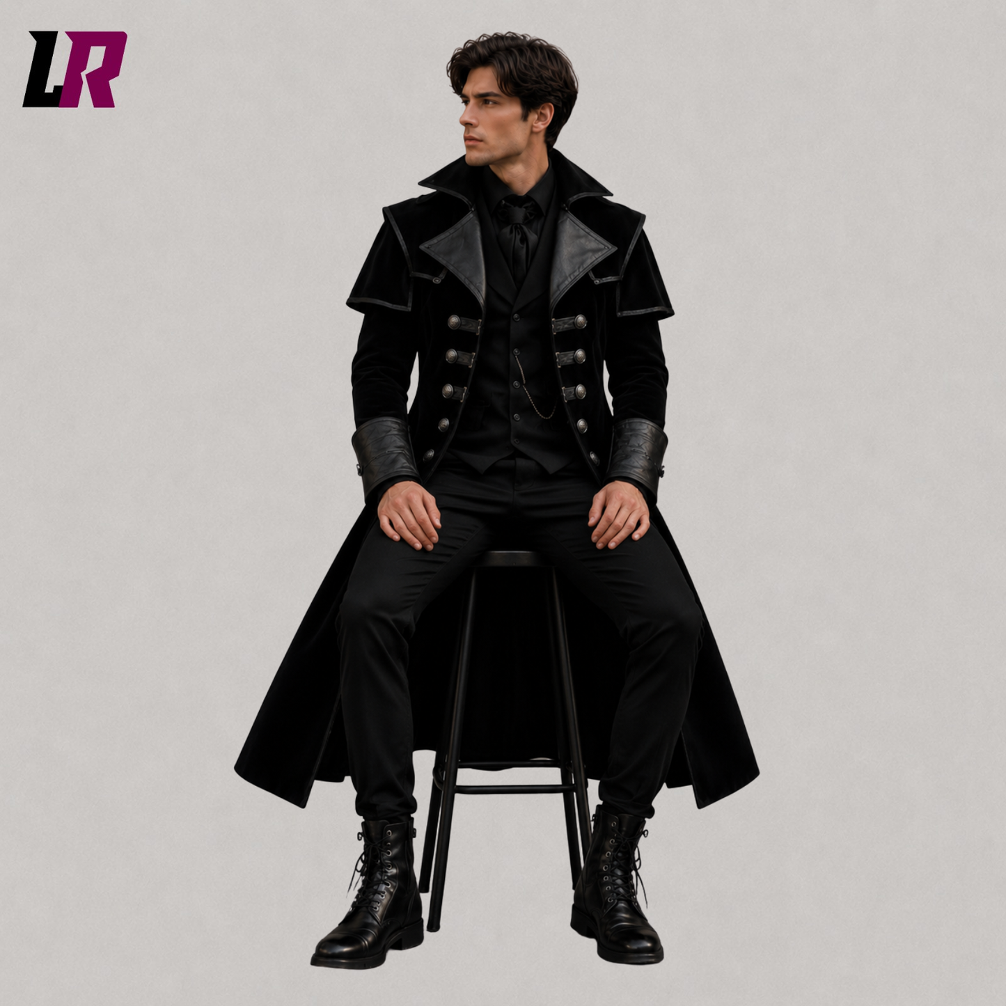 Man sitting on a stool wearing a handmade black velvet Gothic Victorian long coat for weddings and formal occasions