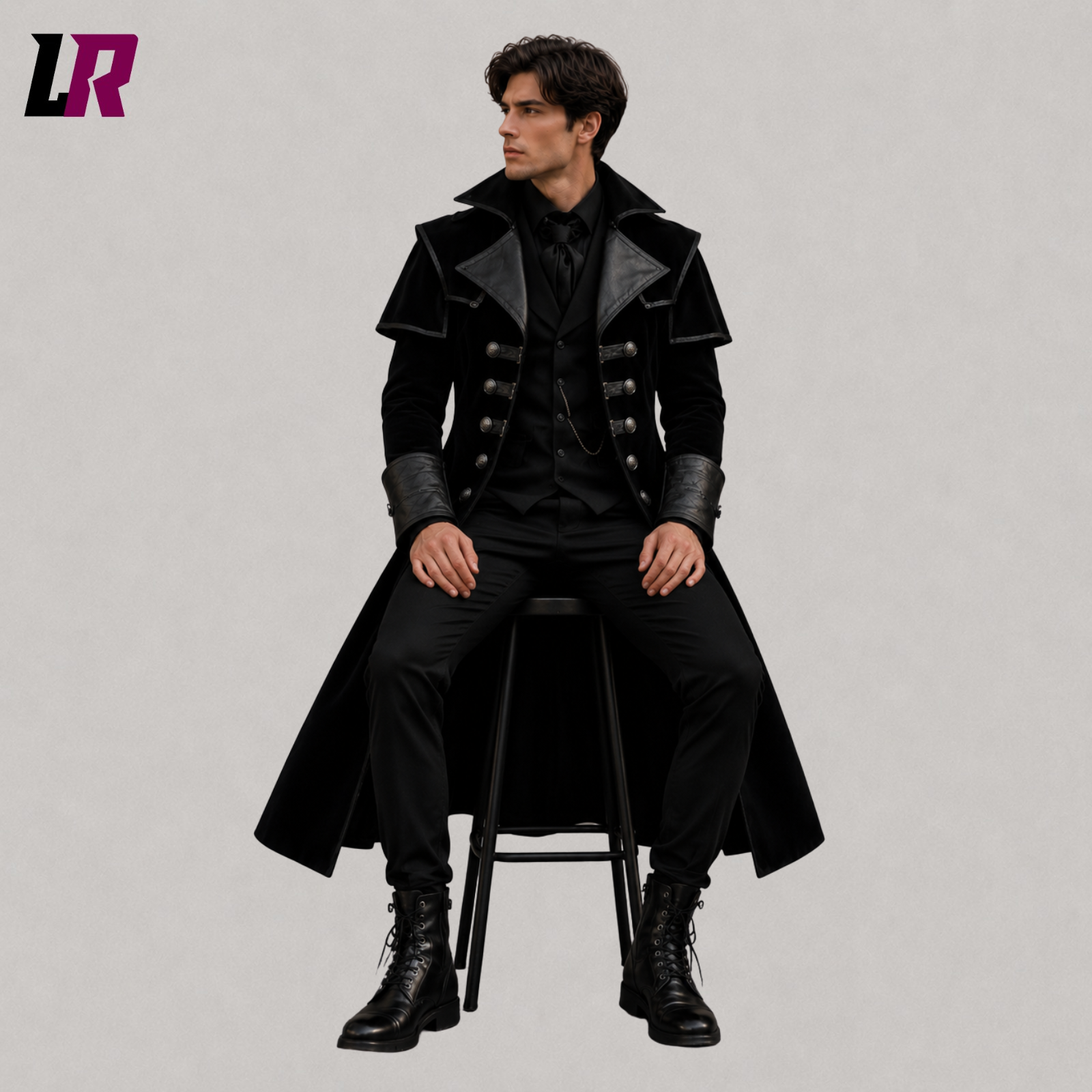Man sitting on a stool wearing a handmade black velvet Gothic Victorian long coat for weddings and formal occasions