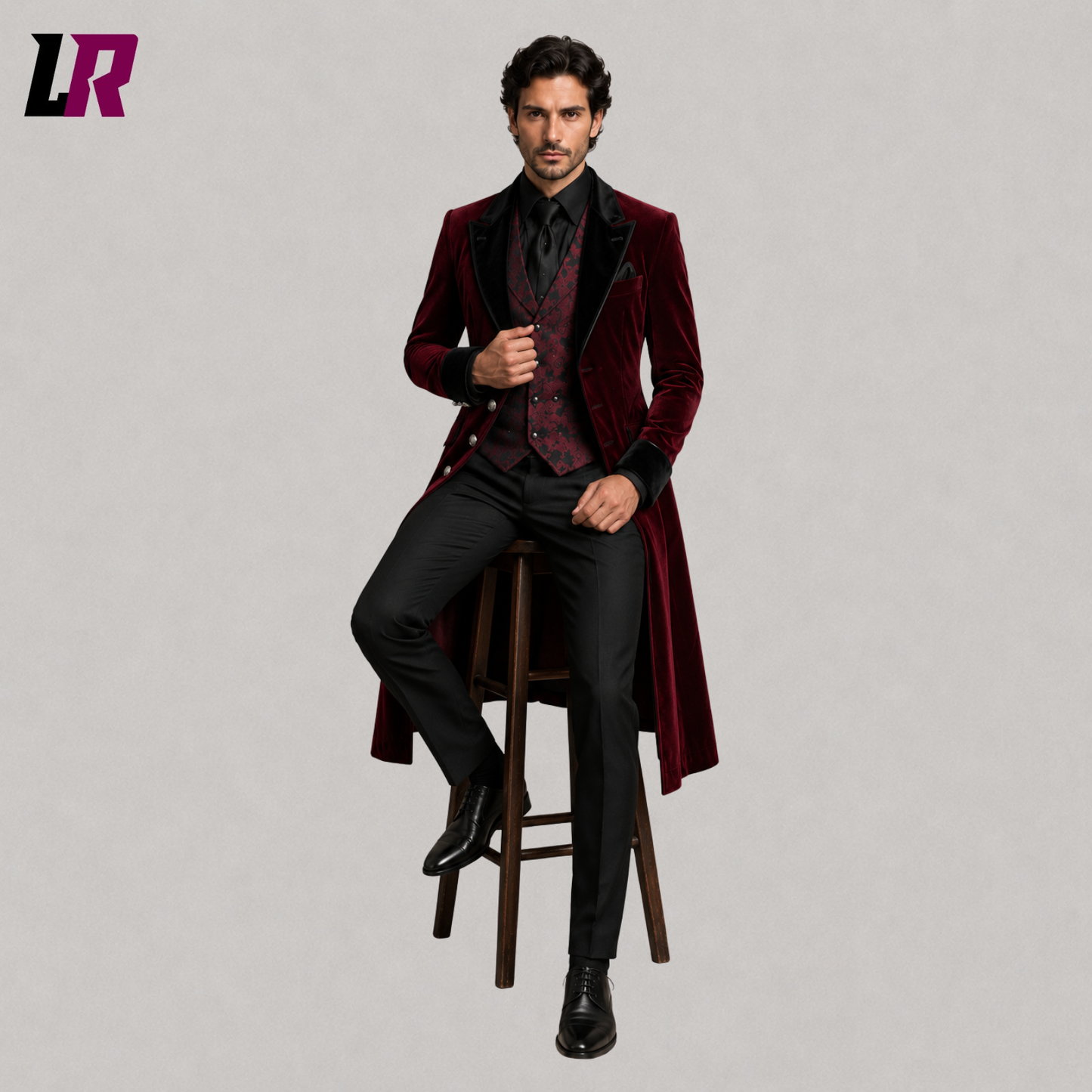 Man sitting on a stool wearing a burgundy velvet Victorian Gothic 3-piece tailcoat suit for weddings and formal occasions