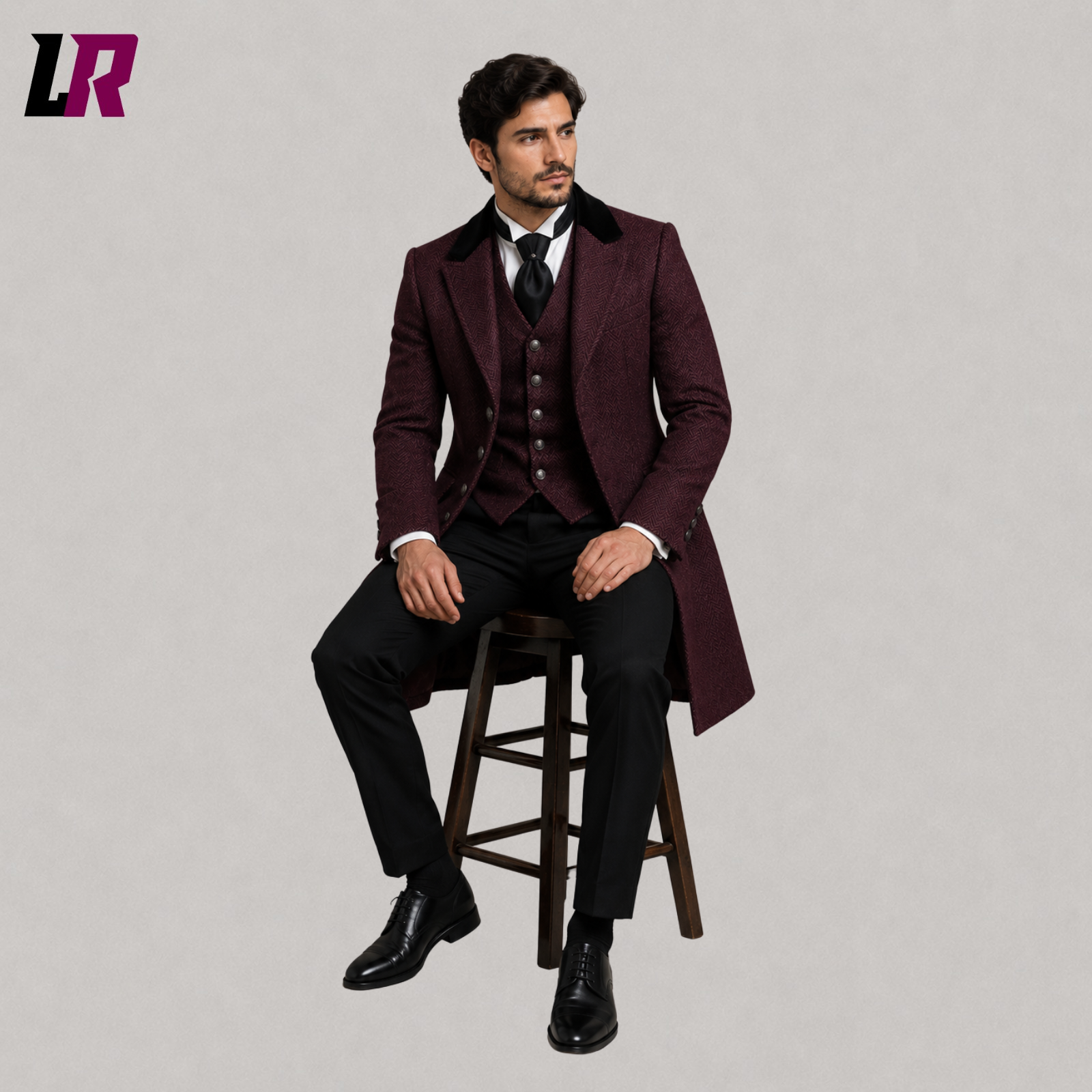 Man sitting on a stool wearing a burgundy herringbone Victorian frock coat suit for weddings and formal occasions