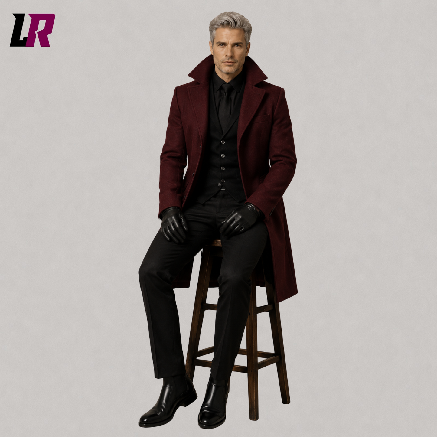 Man sitting on a stool wearing a burgundy Victorian Gothic overcoat for weddings and formal historical occasions