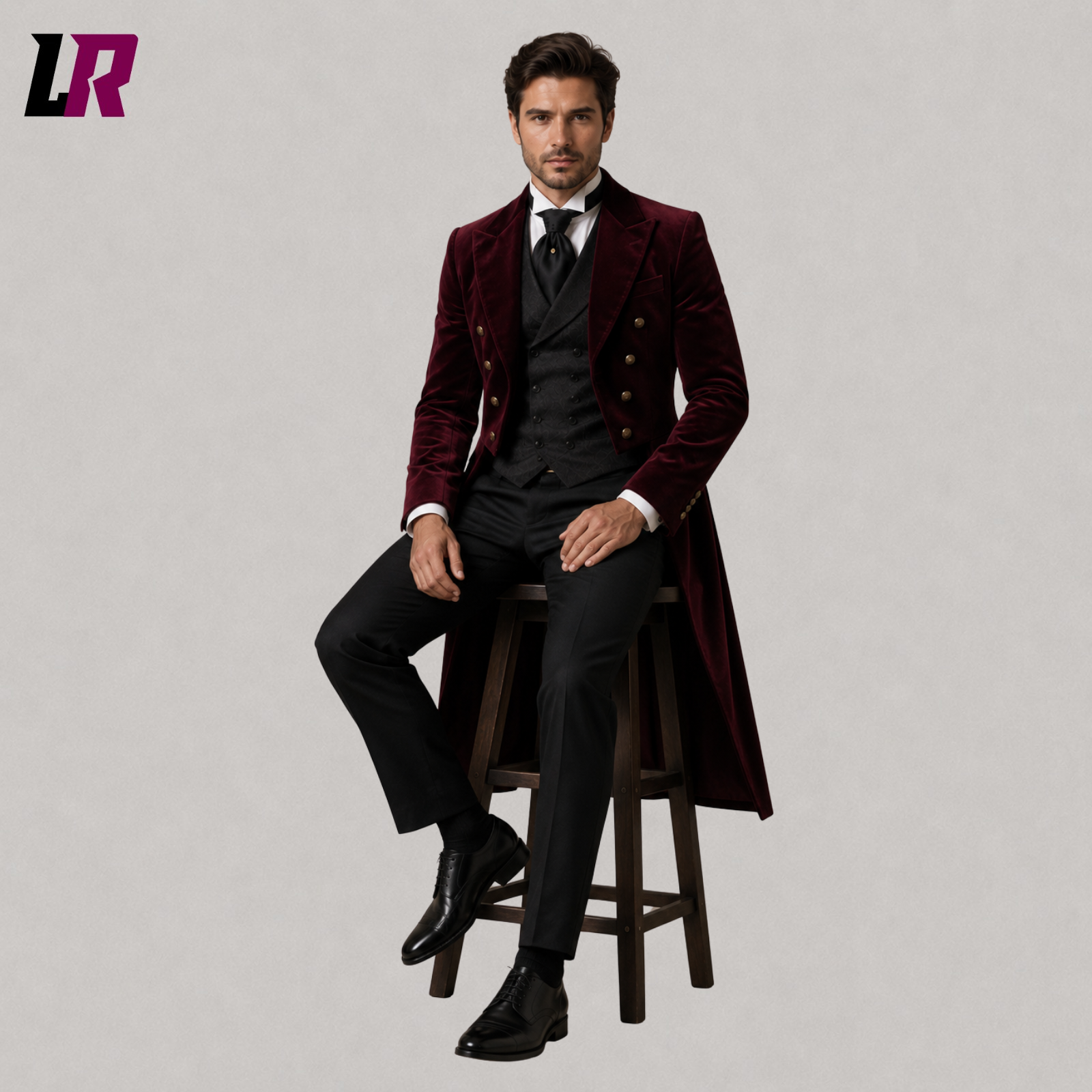 Man sitting on a stool wearing a burgundy velvet Victorian tailcoat suit for weddings and formal occasions