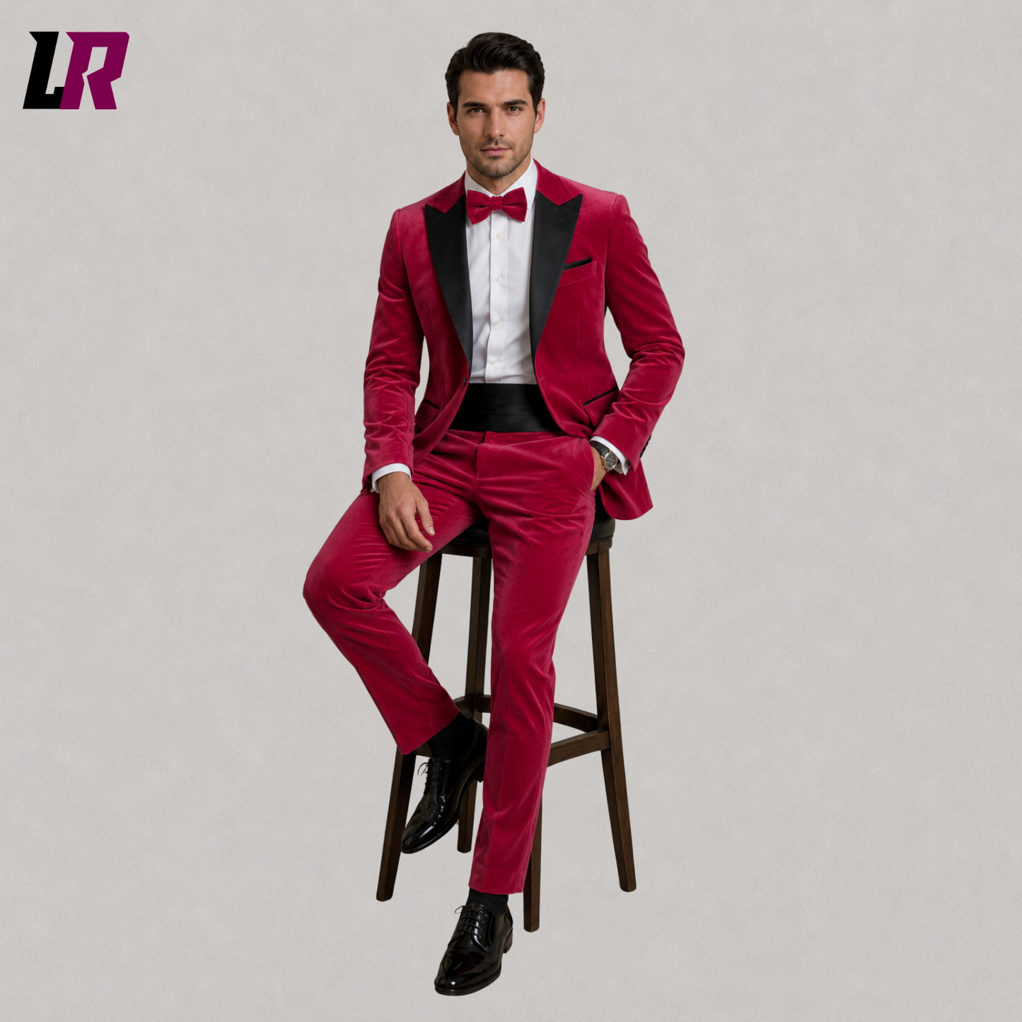 Man wearing a hot pink velvet tuxedo suit seated on a stool in a luxury formal portrait