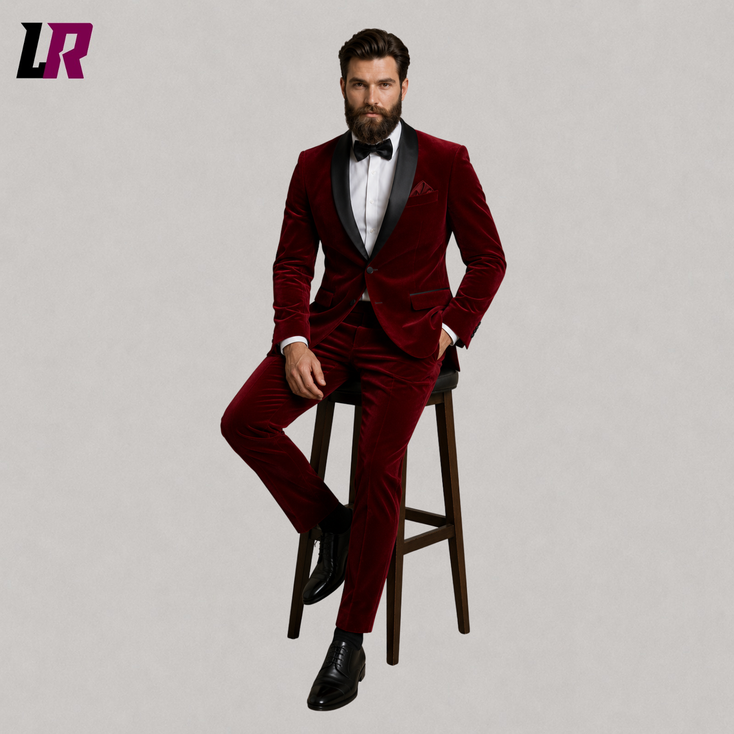 Man wearing a luxury red velvet wedding tuxedo seated on a stool in a formal portrait
