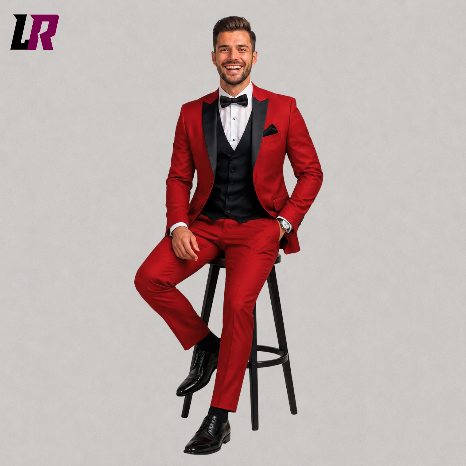 Man wearing a red 3 piece tuxedo suit seated on a stool in a luxury formal portrait