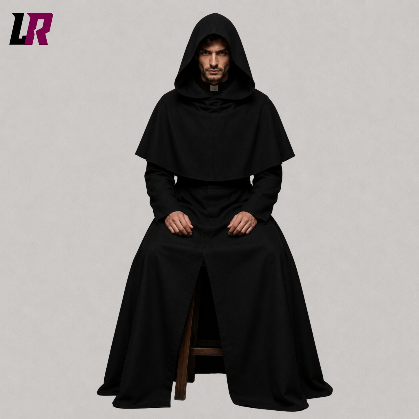 Man wearing a black hooded monk robe seated on a stool in a traditional monastic habit