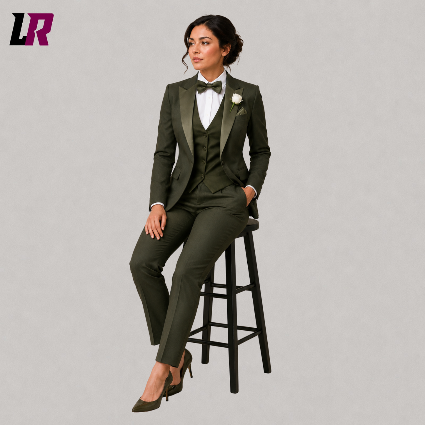 Woman wearing an olive green three piece tuxedo suit seated on a stool in a formal portrait