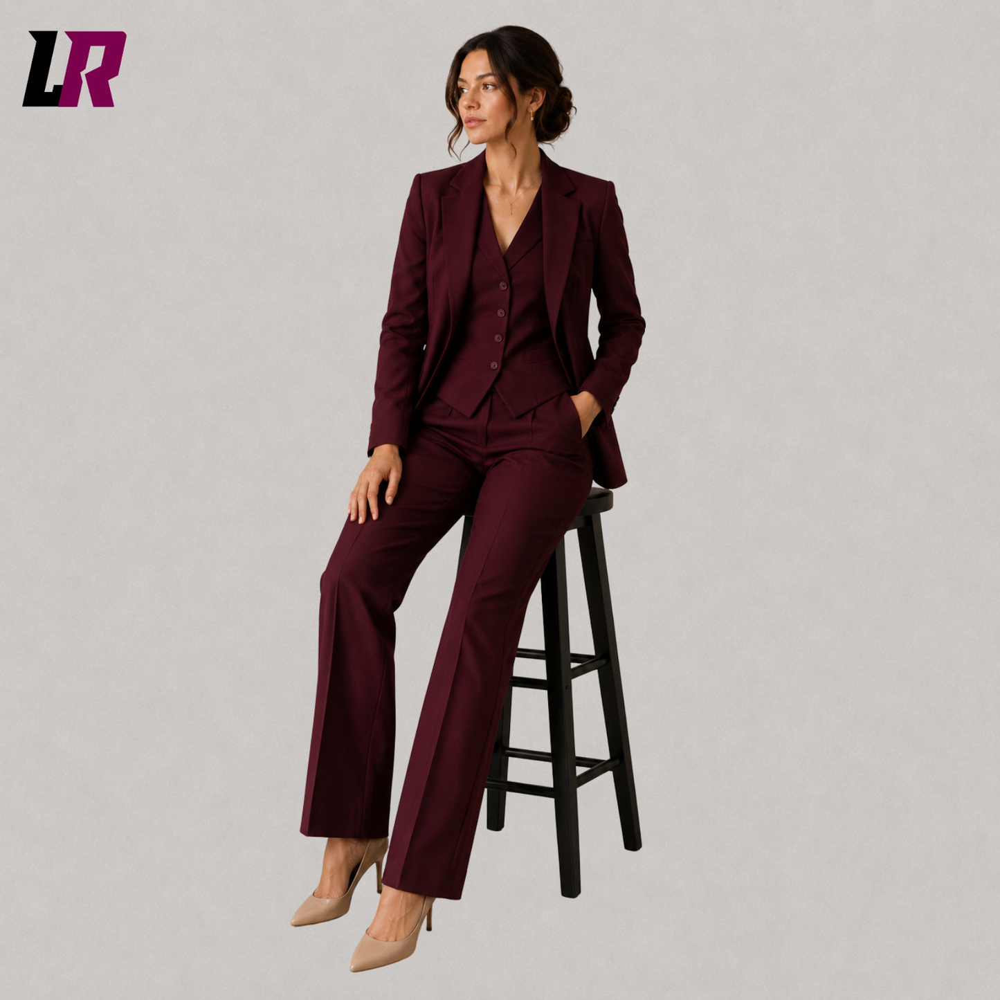 Woman wearing a burgundy formal suit set seated on a stool in an elegant executive portrait