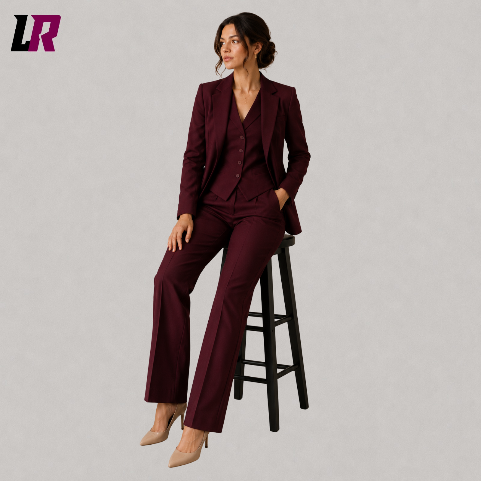Woman wearing a burgundy formal suit set seated on a stool in an elegant executive portrait