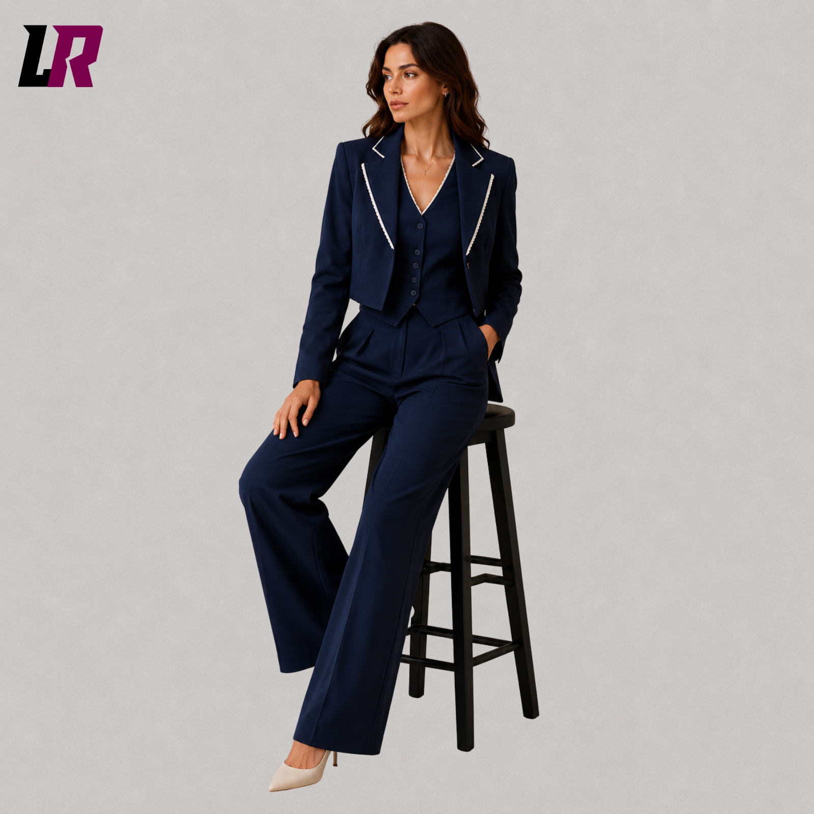 Woman wearing a navy blue three piece pantsuit seated on a stool in a professional portrait