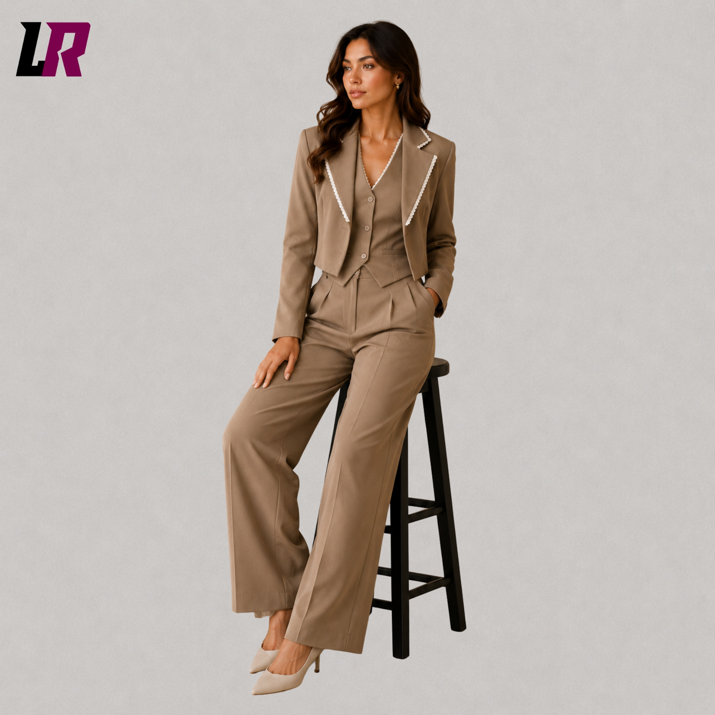 Woman wearing a taupe 3 piece office suit seated on a stool in a professional portrait